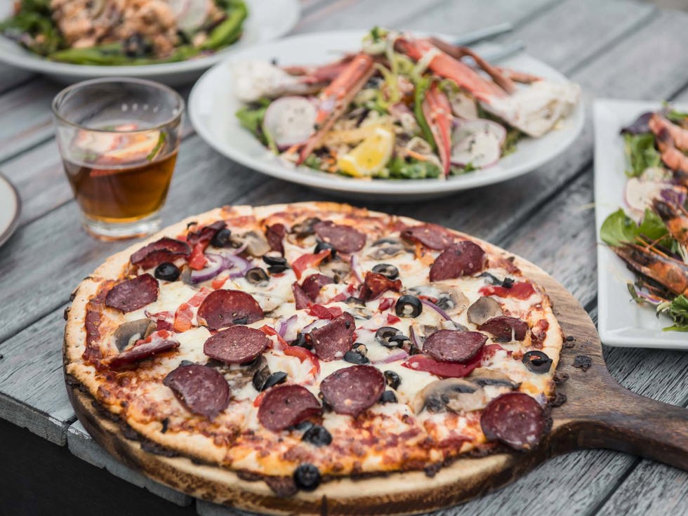 Enjoy choosing from a variety of sharing options at the Boatshed Cafe and Bar like hot stone baked pizzas, smaller plates and more at Punga Cove in the Marlborough Sounds