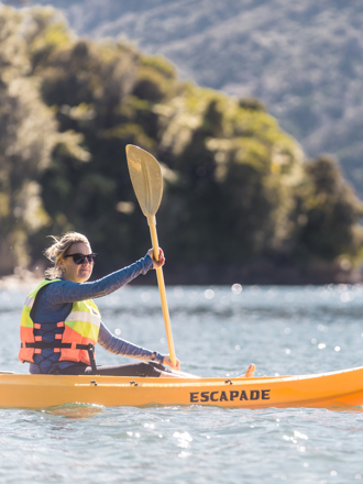 A women admires the view while kayaking around Punga Cove in the Marlborough Sounds in New Zealand's top of the South Island