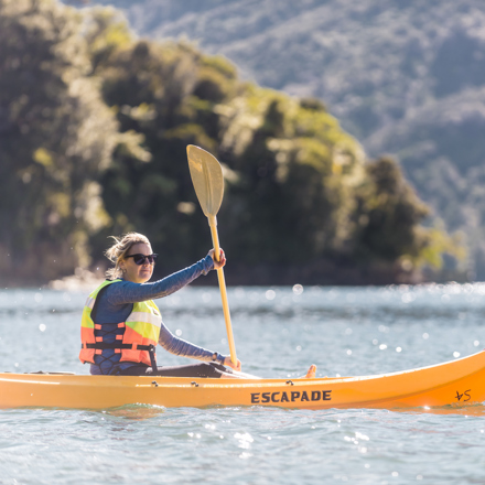 A women admires the view while kayaking around Punga Cove in the Marlborough Sounds in New Zealand's top of the South Island