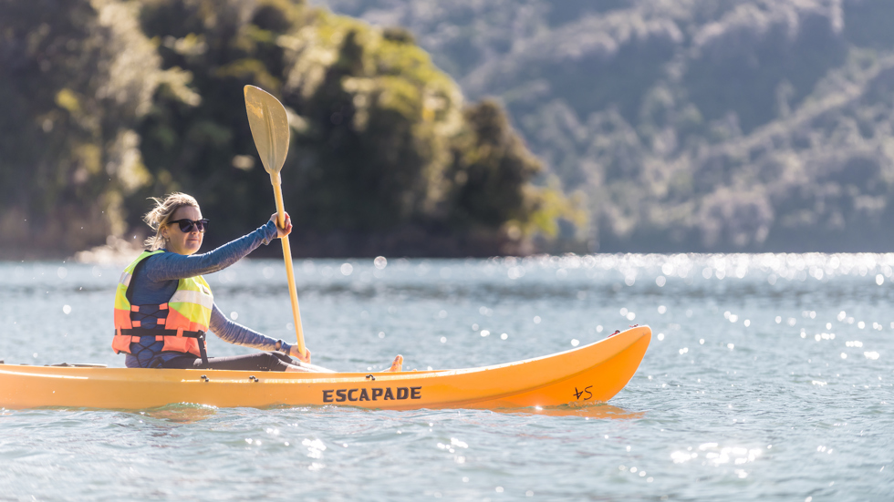 A women admires the view while kayaking around Punga Cove in the Marlborough Sounds in New Zealand's top of the South Island