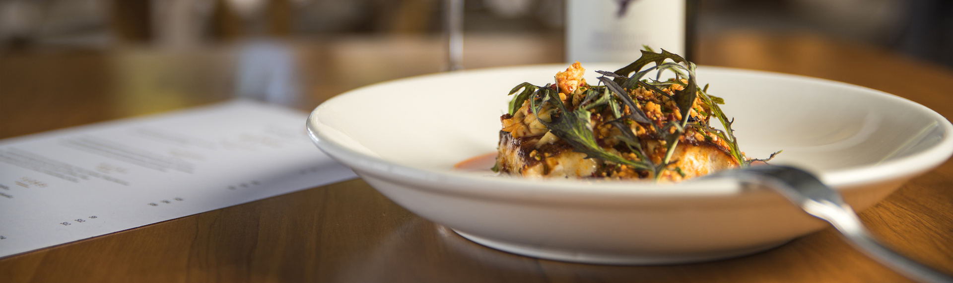 The Punga Fern Restaurant menu can include meals like this fresh Groper dish matched with a glass of local Marlborough wine at Punga Cove in the Marlborough Sounds of New Zealand's South Island