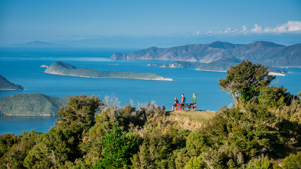 Two walkers admire the Marlborough Sounds view from the top of a hill in New Zealand's top of the South Island