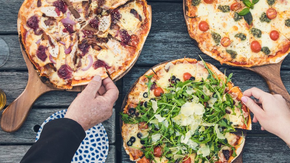 A family dining on the jetty at Punga Cove - a great way to enjoy stone baked pizza and more at the Boatshed Cafe and Bar.