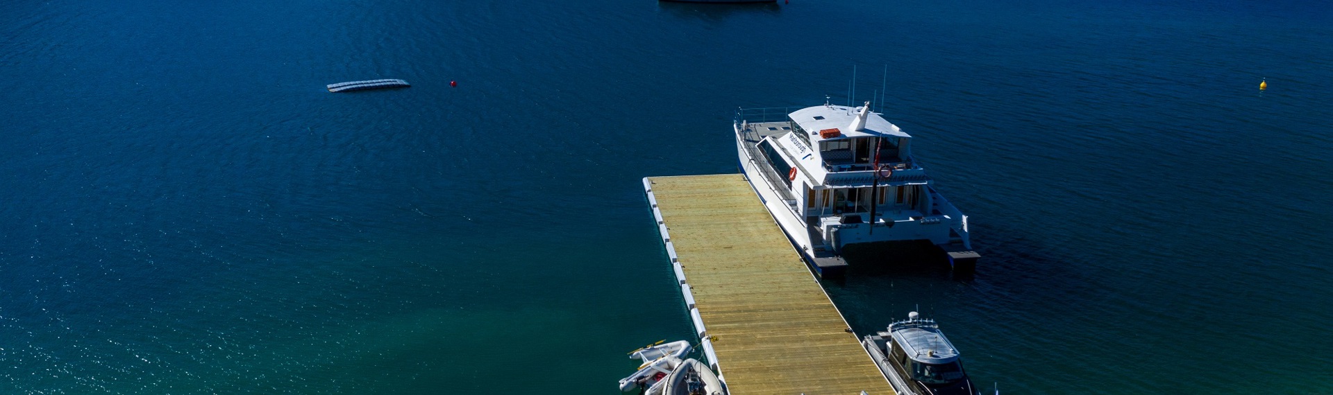 An aerial view of the Punga Cove jetty with a number of vessels parked next to it - there is also moorings available to park vessels