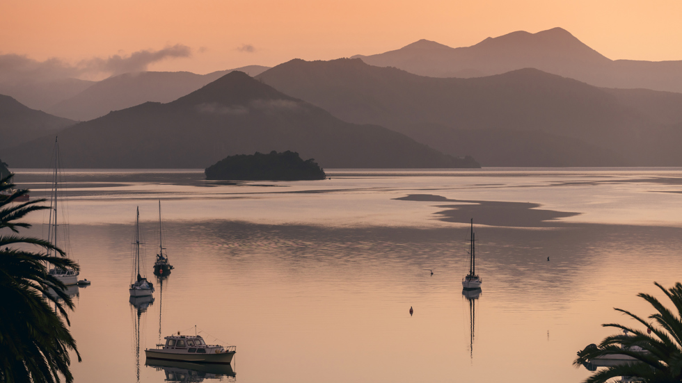 he view from Picton at sunrise over Queen Charlotte Sound/Tōtaranui, with orange skies and water in the Marlborough Sounds, New Zealand.